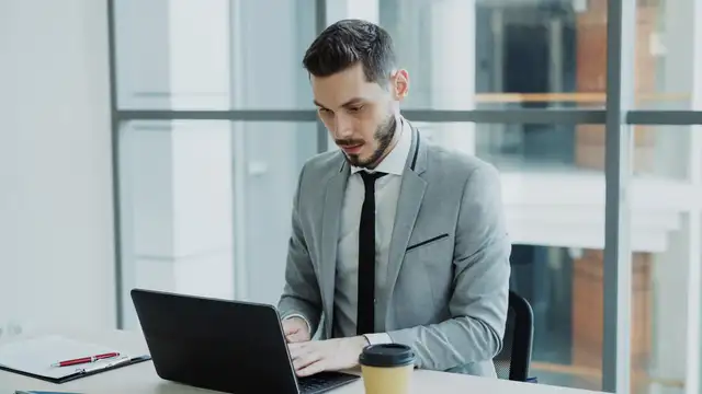 Businessman working on a laptop in a modern office setting.