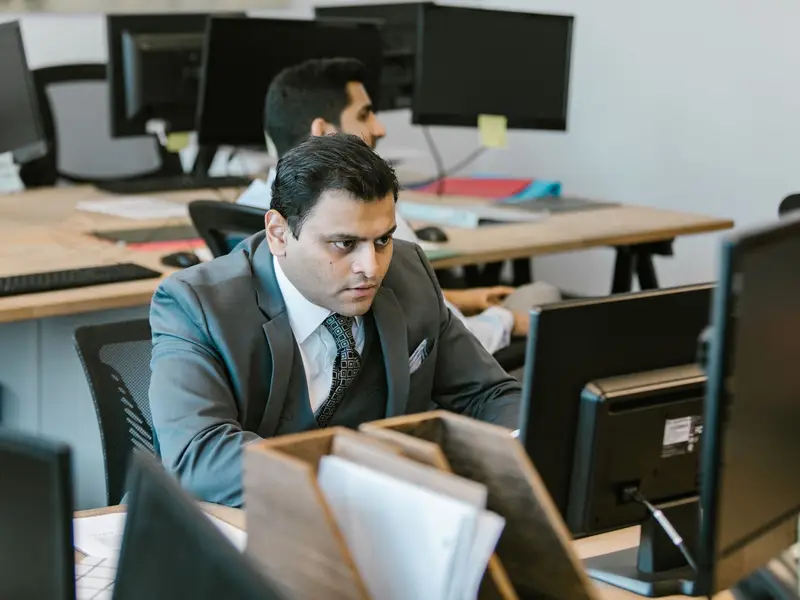 A dedicated businessman in a suit concentrating on work at a modern office desk.