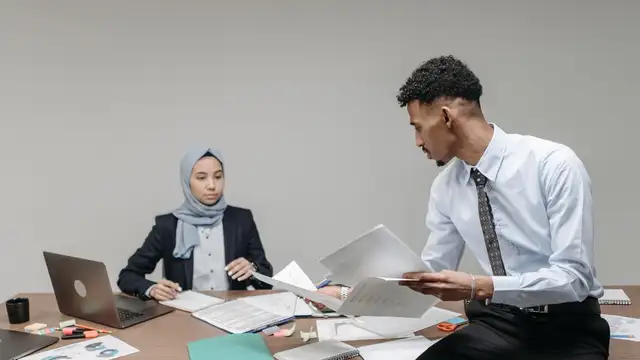 Muslim business professionals collaborating at desk in modern office.